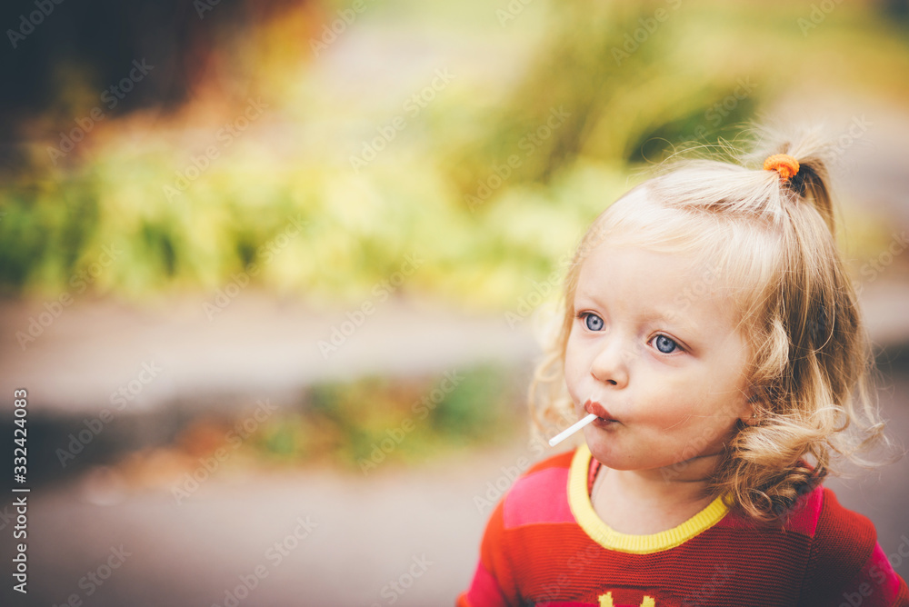 Cute toddler girl with lollipop, blurred background close up Cute toddler girl with lollipop, blurred background close up