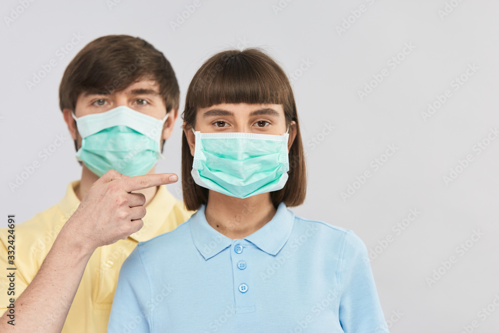 young girl in protection mask and handsome guy point on it with finger