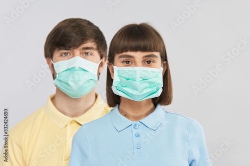 two young persons wearing protection respiratory mask and looking to camera on grey background