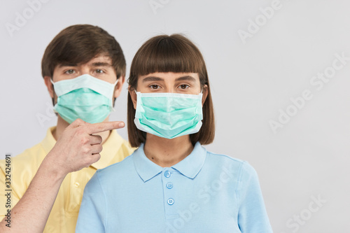 young girl in protection mask and handsome guy point on it with finger