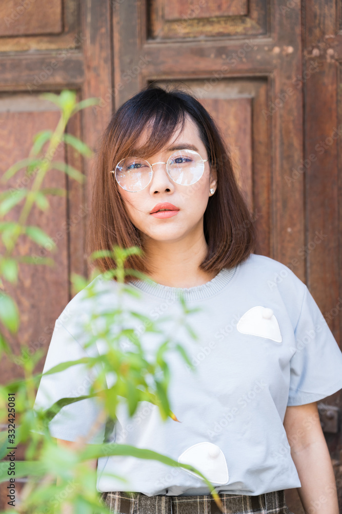 Portrait of fashion woman posing while wearing glasses against wooden door Portrait of fashion woman posing while wearing glasses against wooden door