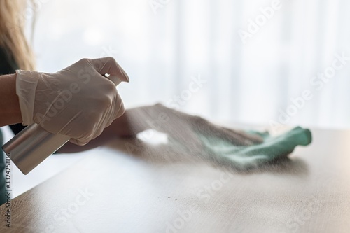 Woman disinfects table with spray disinfectant liquid photo