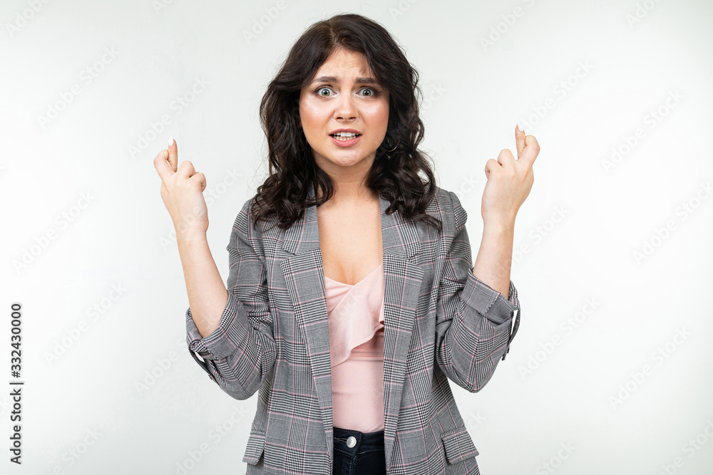 girl in a classic checkered gray jacket prays scratching fingers on a white background girl in a classic checkered gray jacket prays scratching fingers on a white background