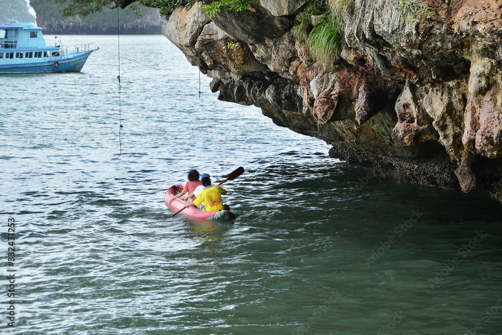 Tourist kayaking near the cliff in Ao Phang-Nga National Park, Thailand.