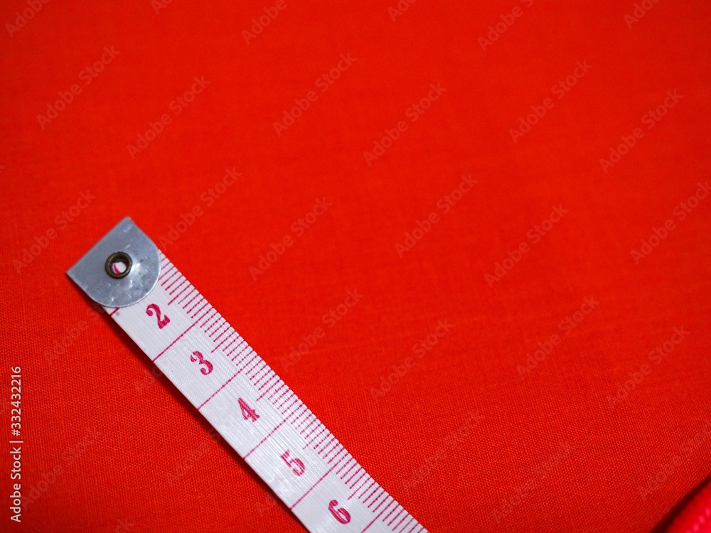 Measurement tape on red color cloth background. Copy space for insert copy text Measurement tape on red color cloth background. Copy space for insert copy text
