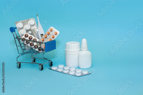 Shopping cart with pills on a blue background . The concept of the medicine of online shopping. Copy space for text