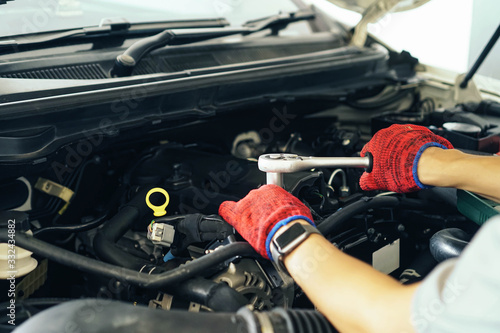 Cropped image of handsome young auto mechanic in uniform repairing car in auto service.selective focus.