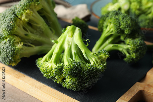 Board with broccoli on grey table, close up. Healthy food