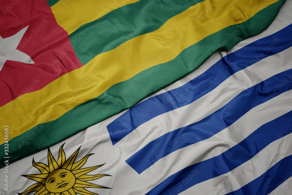 waving colorful flag of uruguay and national flag of togo.