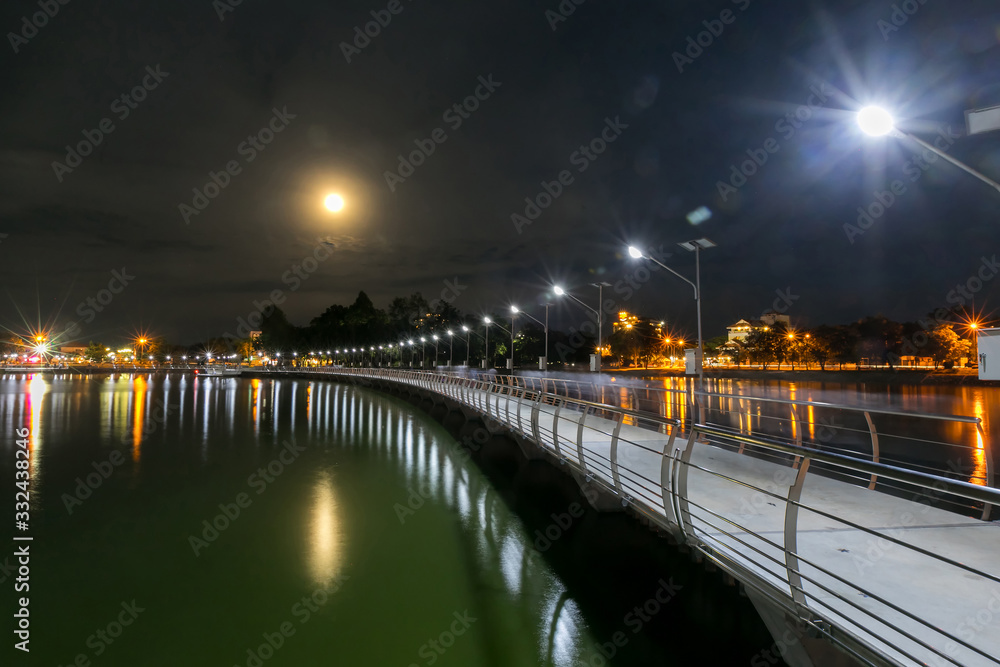 Beautiful lighting of Bridge across buangkaennakorn lake with background of Wat Nong Wang temple and reflection on the water at twilight ,Khonkaen province,Thailand