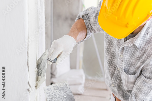 Builder using a trowel to add plaster to a wall photo
