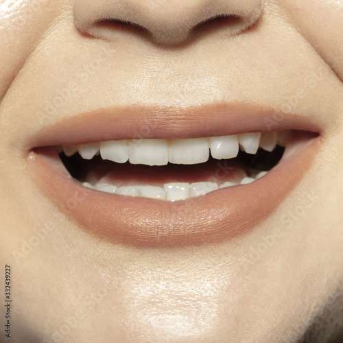 Smiling. Close-up shoot of female mouth with natural nude gloss lips make-up and well kept cheeks skin. Cosmetology  medicine  dentistry and beauty care  emotions and facial expression concept.