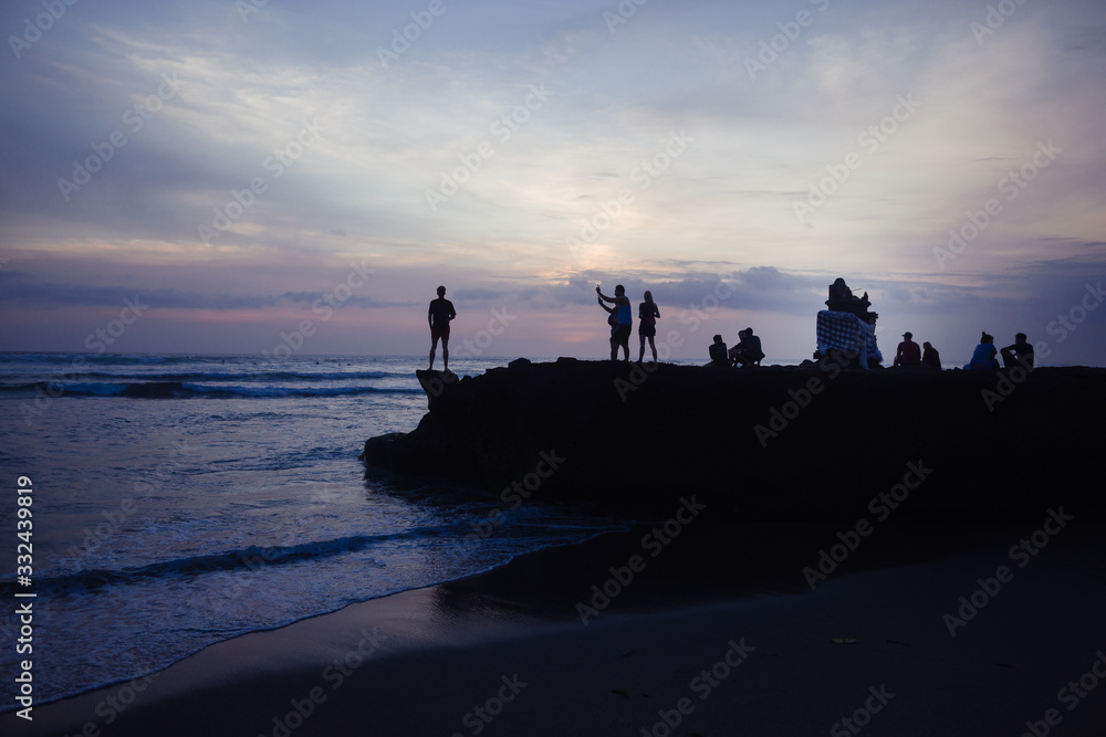 Menschen auf felsen am Strand bei sonnenuntergang 