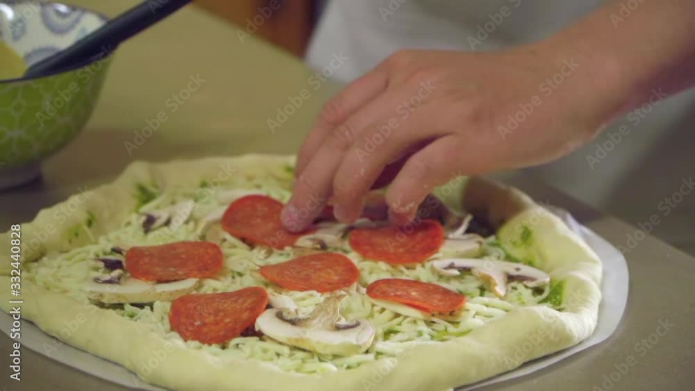 Close Up of Young Man’s Hands Adding Pepperoni to Pizza Close Up of Young Man’s Hands Adding Pepperoni to Pizza