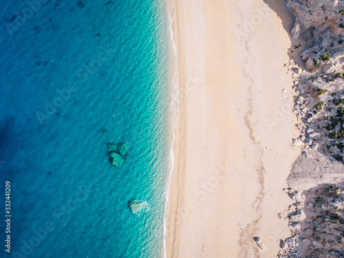 Top-down aerial view of a white sandy beach on the shores of a beautiful turquoise sea.