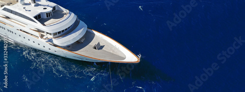 Aerial drone ultra wide photo of luxury mega yacht with wooden deck anchored in deep blue sea of Mykonos island, Cyclades, Greece © aerial-drone