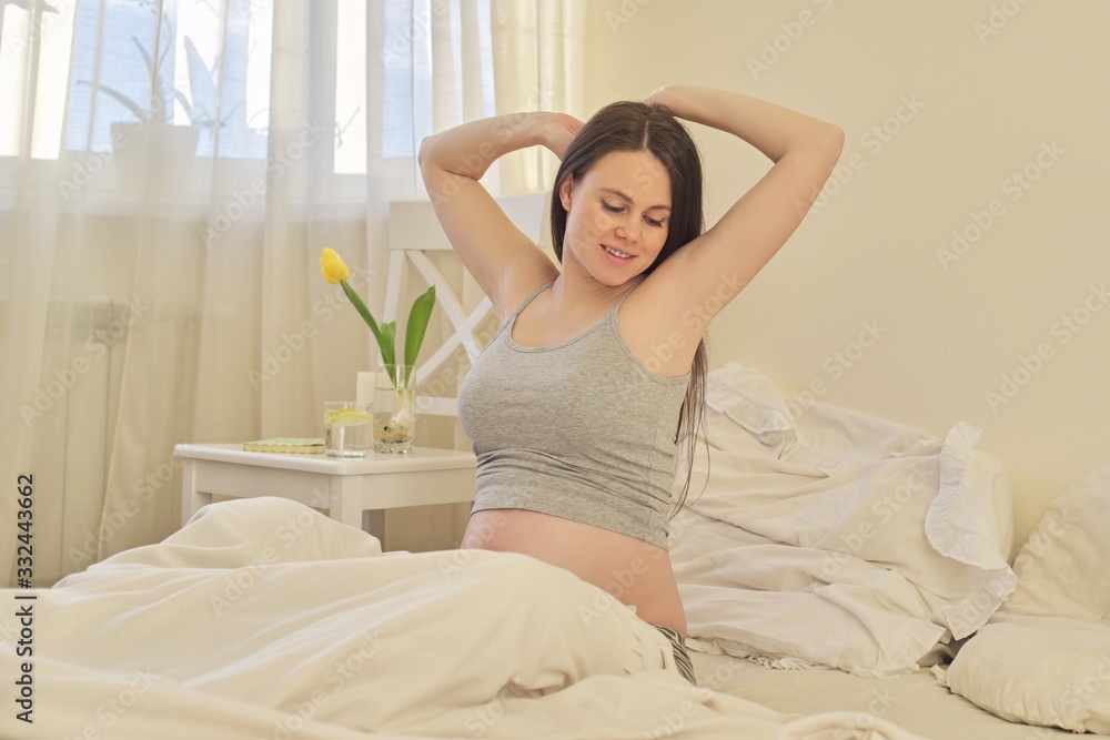 Young beautiful pregnant woman sitting at home in bed Young beautiful pregnant woman sitting at home in bed
