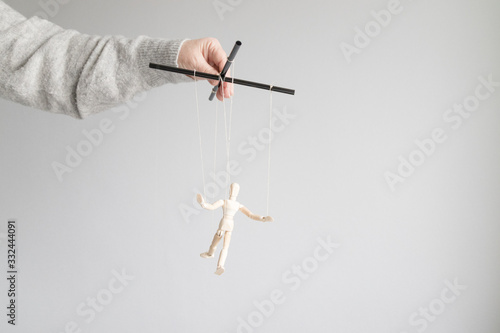 Vászonkép Human hand holds a wooden doll on the clothesline on a gray background with place for text