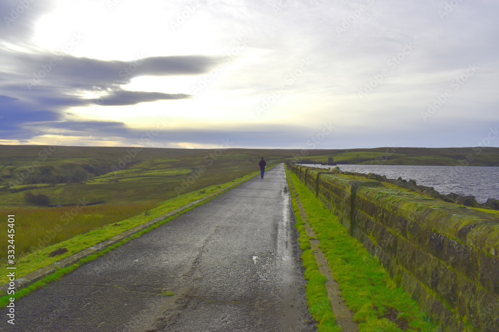 The road through green fields and water in reservoir in the Yorkshire Dales The road through green fields and water in reservoir in the Yorkshire Dales