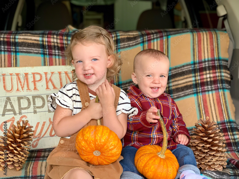 Fototapeta premium Cute little kids with their pumpkins in tailgate of family car