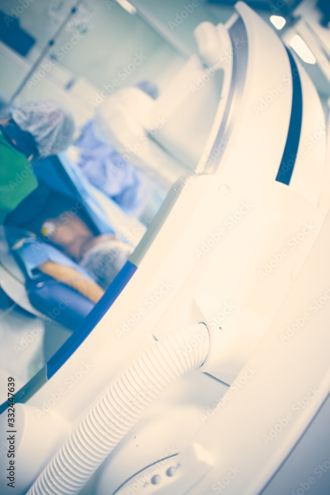 Patient in the x-ray room surrounded by health workers and modern equipment, blurred medical background Patient in the x-ray room surrounded by health workers and modern equipment, blurred medical background