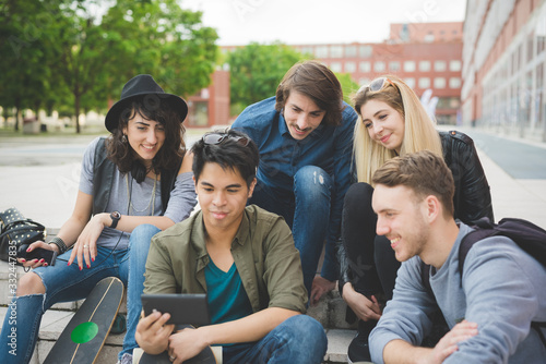 Group of five multiethnic friends outdoor looking at smartphone