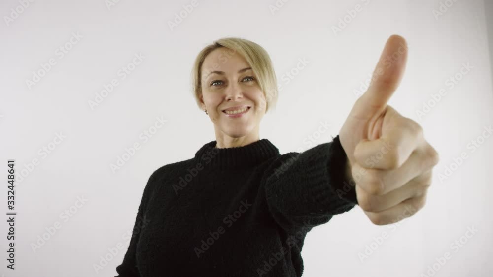 Pleased adult middle aged caucasian blond making thumb up gesture woman against white background in bright interior Pleased adult middle aged caucasian blond making thumb up gesture woman against white background in bright interior