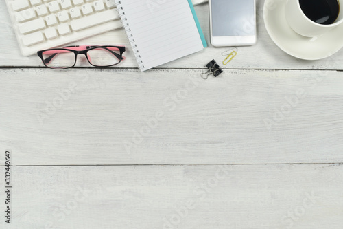 Minimal workspace desk with office supplies  notebook  eyeglasses  coffee  and green plant on wooden background.