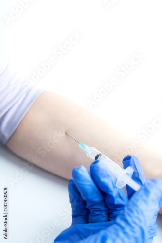 A hand in a medical glove makes an injection, on a white background.