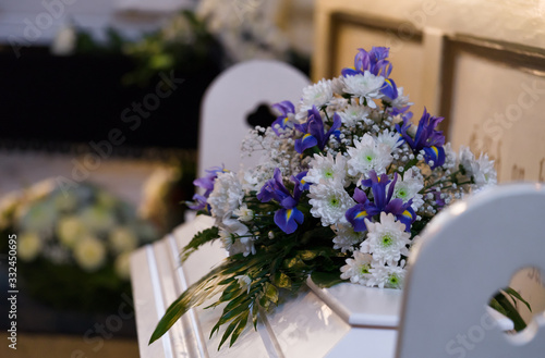 Modest flower arrangement on a white coffin cover next to wall with Bible texts in small Lutheran church, Bouquet from the children of the dead mother. Raasiku, Estonia, Europe. photo