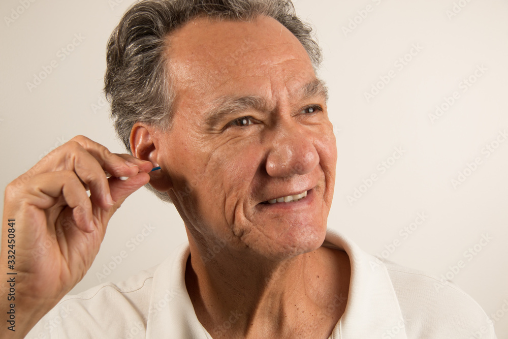 Man Cleaning his Ear with a Cotton Tip Swab Man Cleaning his Ear with a Cotton Tip Swab