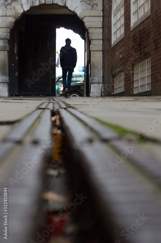 Floor level view of the silhouette of a young man crossing an arch to go outside