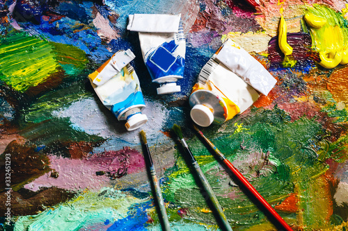 texture of bright colors on a palette with brushes and empty tubes, artist concept