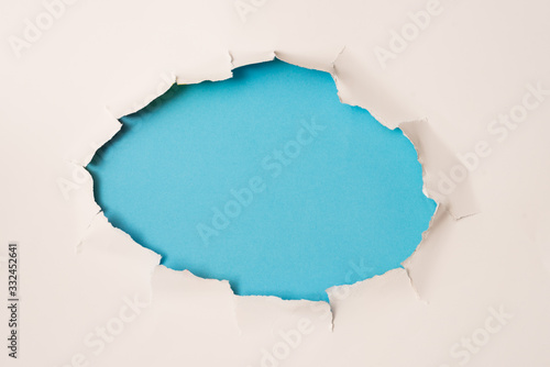 agujero rasgado en papel blanco y fondo azul photo