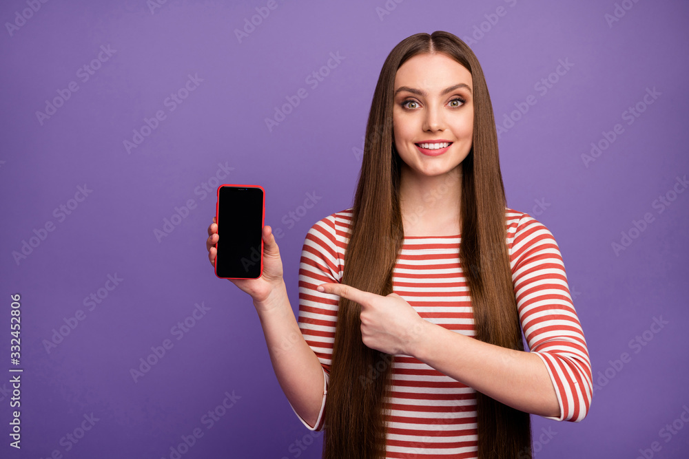 Portrait of positive cheerful girl promoter hold cellphone point index finger advise choose new modern technology offer wear white pullover isolated over violet color background Portrait of positive cheerful girl promoter hold cellphone point index finger advise choose new modern technology offer wear white pullover isolated over violet color background
