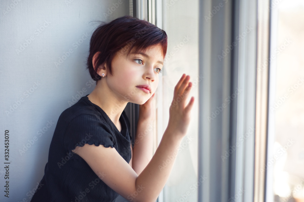 Sad little girl looking out window touching glass by hand. Child during quarantine because of pandemic of coronavirus staring outside through window. Isolation and self isolation Sad little girl looking out window touching glass by hand. Child during quarantine because of pandemic of coronavirus staring outside through window. Isolation and self isolation