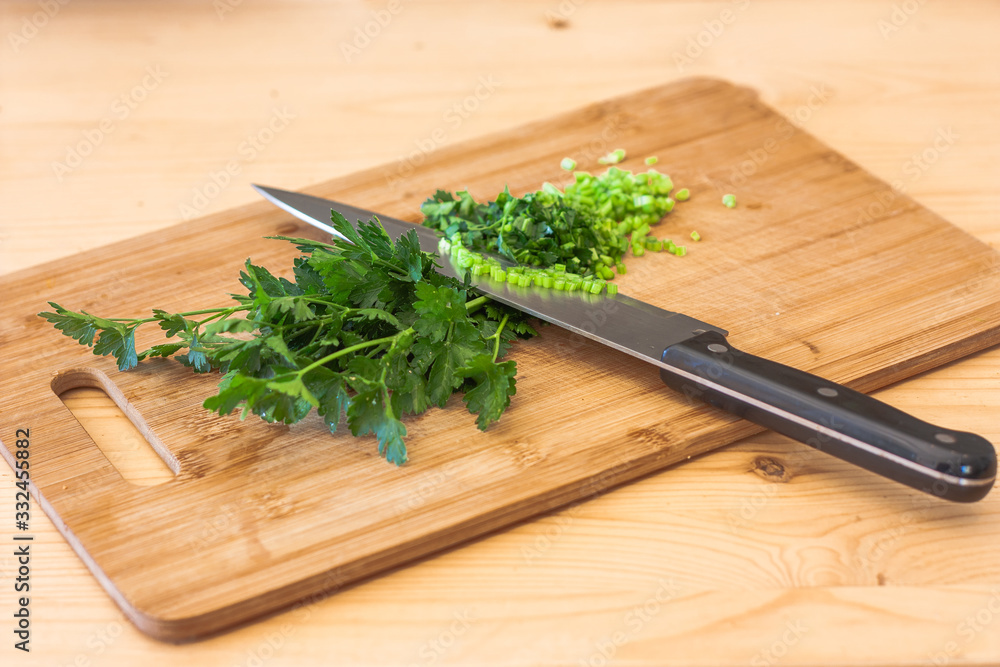 Fresh parsley cut on wooden cutting board with chef's knife Fresh parsley cut on wooden cutting board with chef's knife
