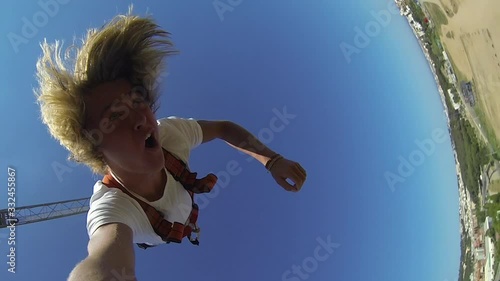 Young man with long blonde hair bungee jumping with a gopro in Lloret de Mar, Spain photo