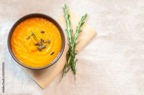 Pumpkin soup decorated on a table with a sprig of rosemary