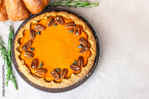 Pumpkin homemade pie on a gray linen background with top view of food ingredients for decoration
