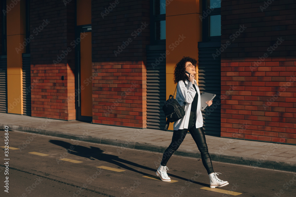 custom made wallpaper toronto digitalGorgeous student with curly hair is walking while having a phone discussion and holding laptop