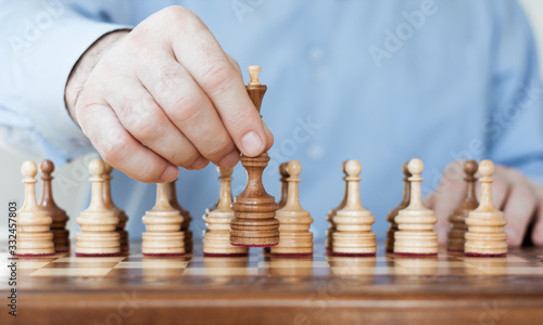 Strategy concept, hand of businessman moving wooden chess figure in play, management or leadership competition success background.