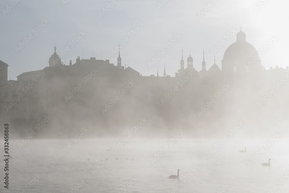 view of the river and buildings of Prague in the fog