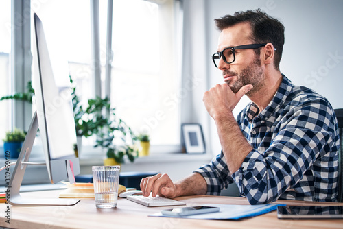 Photography Thoughtful freelancer looking at computer while working from home office