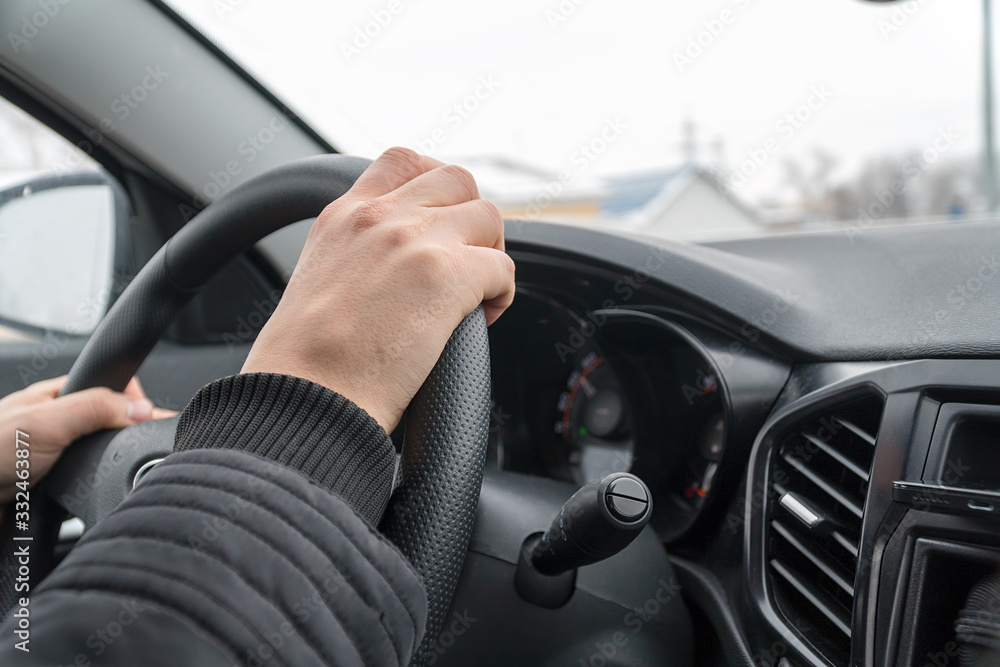 Man drives a car while keeping his hands on the steering wheel