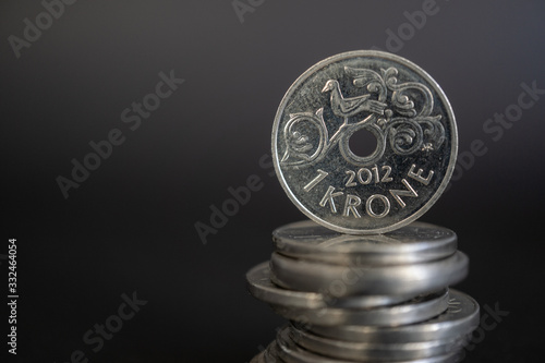 Φωτογραφία Close-up shot of norwegian one krone coin standing on stack of coins against black background