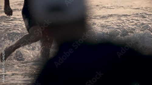 Slow-motion of a swimmer legs running out of the water at the beach