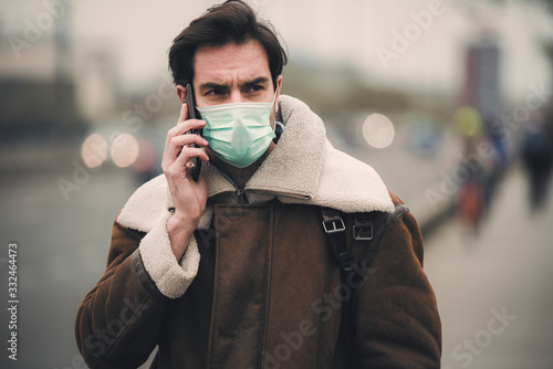 Single male with mask care about his health and have a chat on his mobile