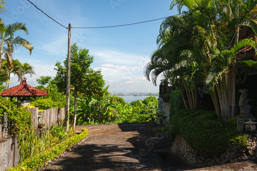 Tropical landscape overlooking the road through the village, palm trees and the ocean.