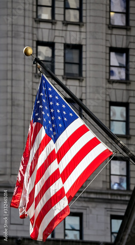 American flag with building facade in background, selective focus, New York City, USA.